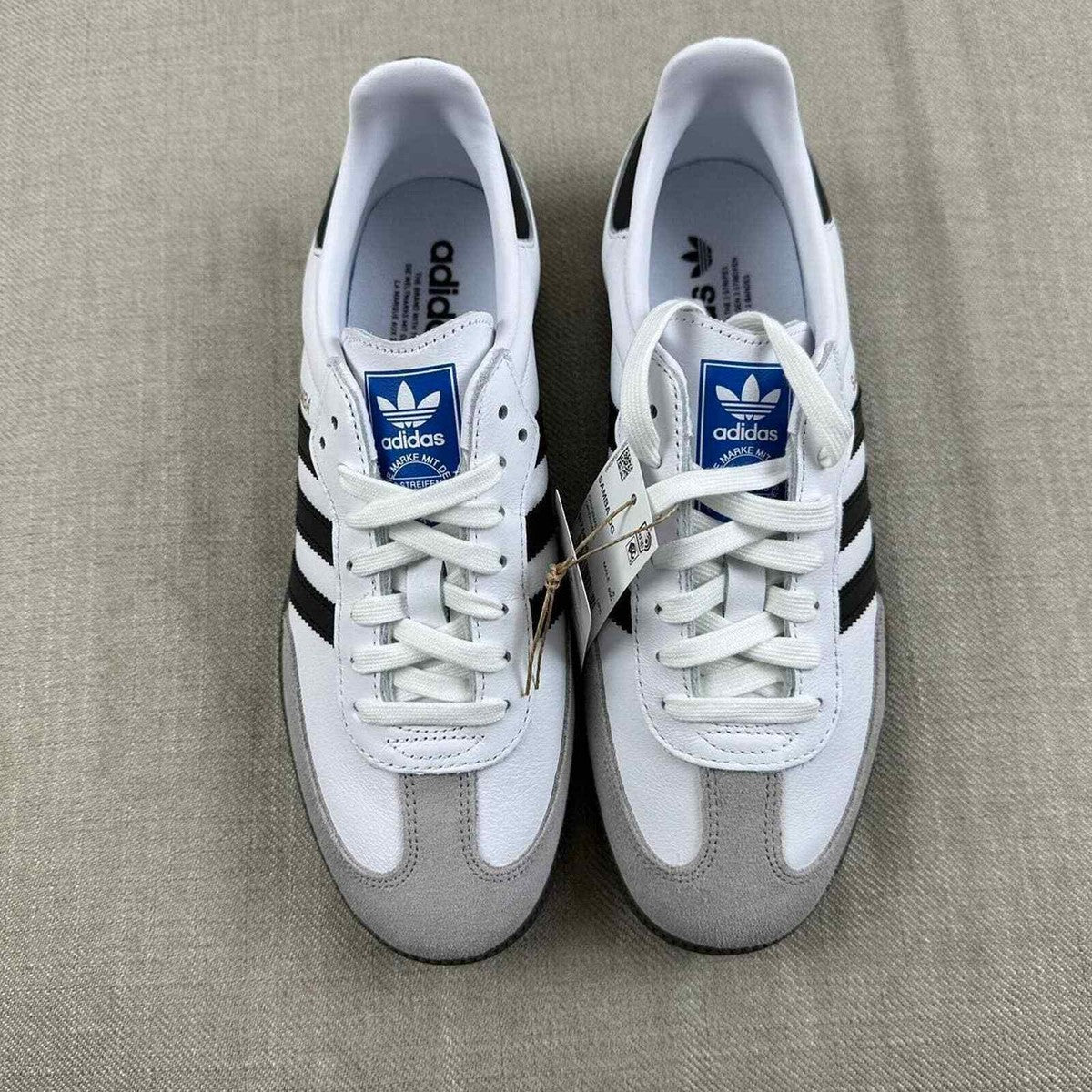 The Adidas Originals Samba OG sneaker features a crisp white leather upper accented by black serrated three-stripes and a classic translucent gum rubber sole