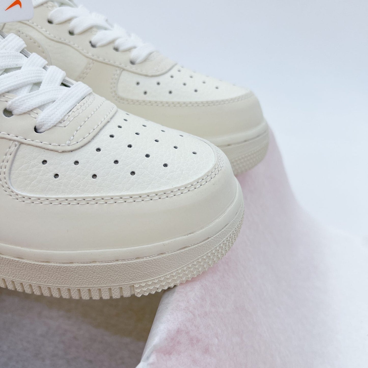 These cream-white Nike Air Force 1 sneakers feature red "Noah" branding accents and a matching circular logo keychain