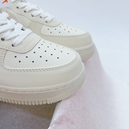 These cream-white Nike Air Force 1 sneakers feature red "Noah" branding accents and a matching circular logo keychain