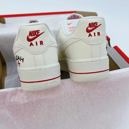 These cream-white Nike Air Force 1 sneakers feature red "Noah" branding accents and a matching circular logo keychain